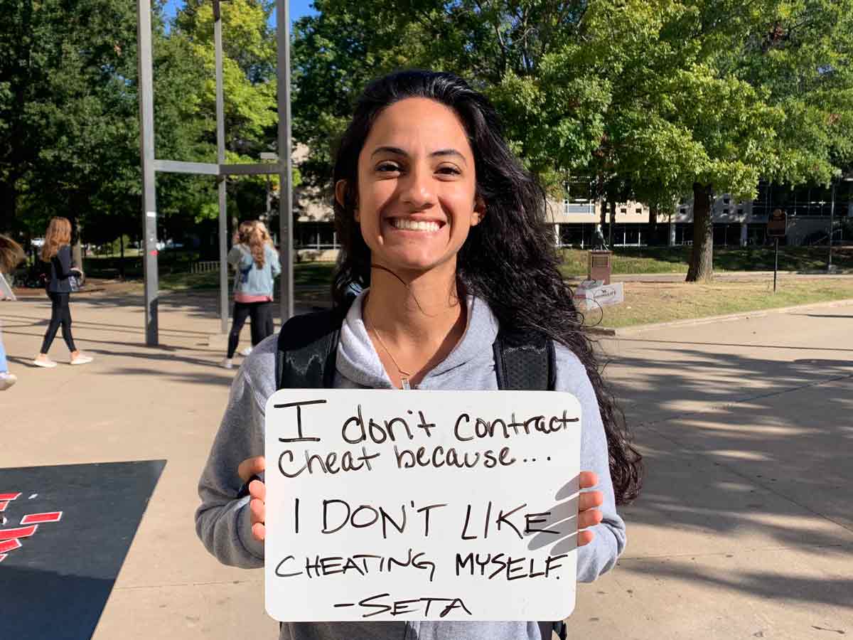 a student volunteer standing outside of the union with a sign saying- I don't cheat because I don't like cheating myself